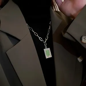 Close-up view of silver mahjong Fa character pendant necklace with sparkling stones on blazer
