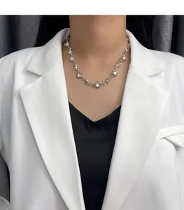 Detail view of a silver-toned thorny choker necklace with moonstones on a model.