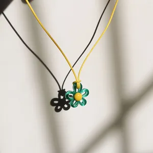 Detail einer grünen Blumenkette, die einen Schatten auf weißen Hintergrund wirft