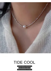 Dettaglio di una collana di perle d'argento luccicanti con una singola perla elegante