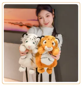 Detailed view of soft plush tiger backpacks in white and orange held by female model.