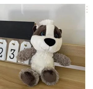Close-up detail of a soft grey and white badger forest animal plush toy on a wooden desk