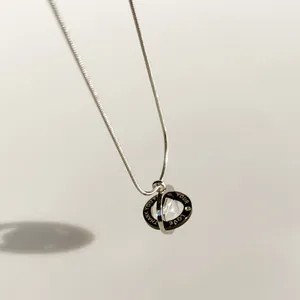 Detailaufnahme einer silbernen Saturn-Halskette mit 'THANK YOU FOR YOUR LOVE'-Gravur