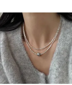 Dettaglio di una collana in argento scintillante a due strati con perla grigia.