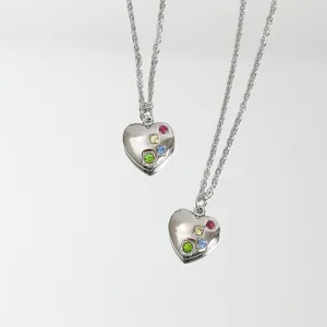 Vista detallada del collar de corazón plateado con incrustaciones multicolores