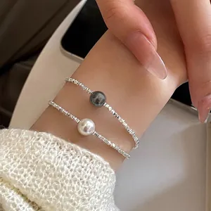 Collana minimalista in argento con perle eleganti indossata come bracciale al polso.
