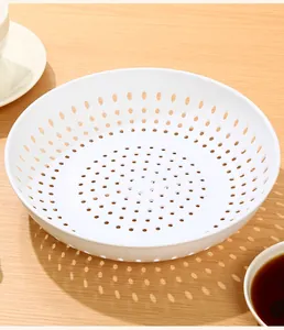 Detailed view of white plastic circular draining plate with uniform perforated design