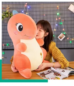 Suave cojín de peluche de dinosaurio naranja sostenido por una niña en una habitación.