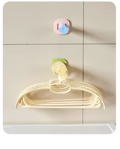 Stackable plastic clothes hangers hanging on a decorative floral wall hook in a laundry room.