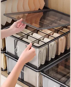 Close-up of hand opening a transparent smoky grey socks and underwear storage box.