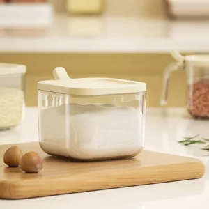 Minimalist square clear seasoning jar with cream lid on wooden cutting board in kitchen