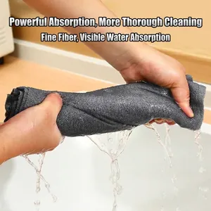 Highly absorbent grey microfiber cleaning cloth being wrung out by hand over a sink.