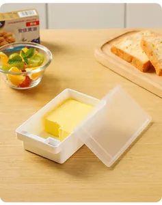Vista detallada de un recipiente para mantequilla con tapa sobre una mesa de madera