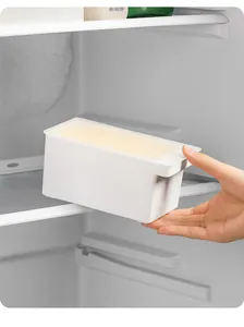 Vista detallada de una caja de mantequilla blanca colocada en un estante del refrigerador para orden