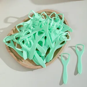 Gratte-langues jetables vert menthe sur un plateau en bois pour l'hygiène buccale