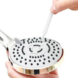 Hand holding a mini white gap cleaning brush to clear silicone shower head nozzles