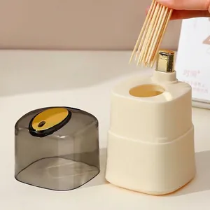 Automatic push-type toothpick dispenser in cream with transparent grey lid and gold button