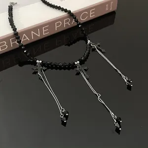 Detail of black beaded necklace with crystal cross pendants and long chain tassels