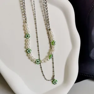 Detailweergave van dubbellaagse kralenketting met witte parels en groene madeliefjes