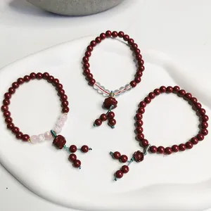 Nahaufnahme von drei roten Zinnober-Perlenarmbändern mit Blumenanhängern im Retro-Stil