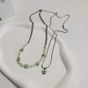 Detailopname van gelaagde ketting met witte parels en groene madeliefjes kralen