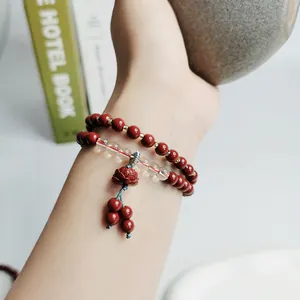 Detailaufnahme eines neuen chinesischen Cinnabarit-Perlenarmbands mit Lotus-Anhänger