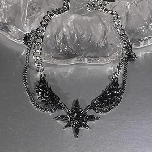 Detailed view of dark punk wing and star pendants on a layered silver-toned chain necklace