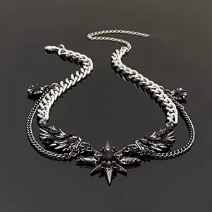 Detail of dark gothic punk necklace with silver wings and star pendant on black surface.