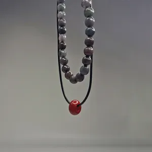 Vue macro détaillée d'un collier double épaisseur avec pierres naturelles facettées et perle rouge