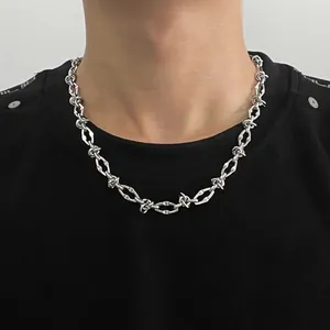 Close-up of silver industrial chain necklace with barbed wire design on black shirt.