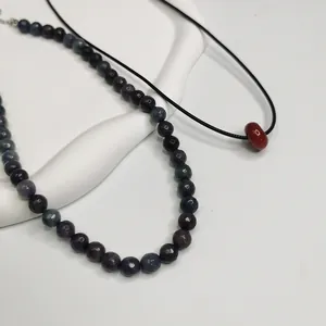 Gros plan d'un collier de perles en pierre naturelle avec un pendentif perle rouge