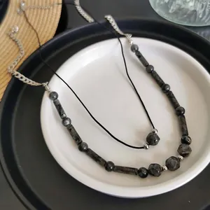Vista dettagliata della collana di pietre naturali fatta a mano con cordino nero su piatto