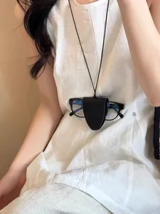 Dettaglio di una clip magnetica in pelle per occhiali indossata come collana alla moda.