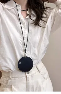Primo piano di una collana a bustina rotonda in pelle nera per auricolari e chiavi