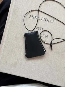 Dettaglio del ciondolo portaocchiali magnetico in pelle nera con cuciture bianche a vista
