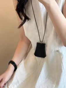 Dettaglio della collana con clip magnetica per occhiali da sole in pelle nera.