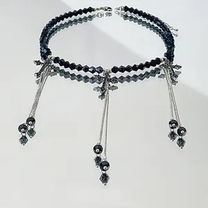 Detailed shot of black beaded choker necklace featuring silver tassels and cross charms