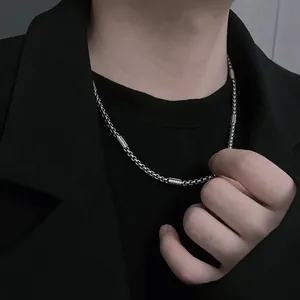 Detail shot of a minimalist silver titanium steel chain necklace on a male model's neck.