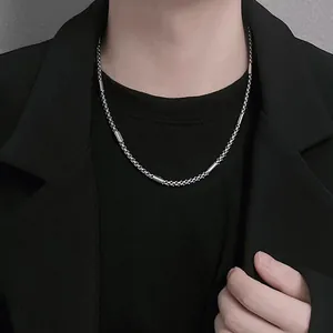 Close-up of minimalist silver titanium steel chain necklace on a male model in black blazer