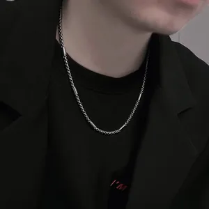 Close-up detail of a minimalist titanium steel chain necklace worn with a black blazer