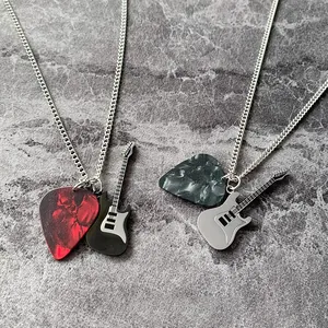 Dettaglio di plettro rock e ciondoli a forma di chitarra elettrica su catene