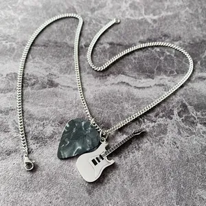 Dettaglio del plettro per chitarra rock e del ciondolo per chitarra elettrica argento.