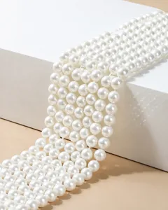 Detailed close-up of glossy white South Sea shell pearls on a minimalist white stand.