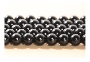 Vue rapprochée montrant la texture polie des perles d'obsidienne noire naturelle.