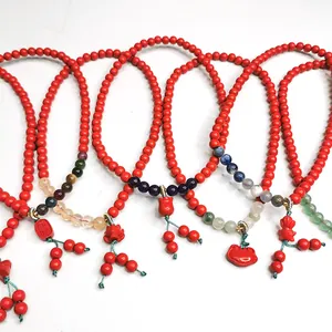 Detailansicht traditioneller roter Zinnober-Armbänder mit bunten Edelsteinen und Anhängern