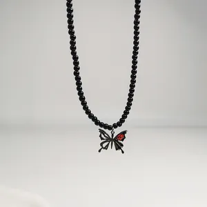 Detailaufnahme einer schwarzen Perlenkette mit Schmetterlingsanhänger und rotem Stein
