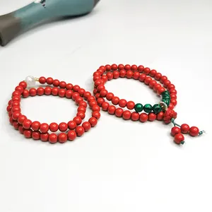 Detailansicht zweischleifiger roter Zinnober-Armbänder mit grünen Akzenten und Quaste