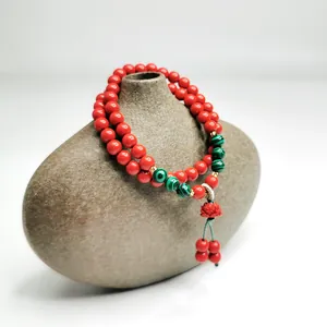 Detaillierte Ansicht eines roten Zinnober-Armbands mit Lotus-Anhänger auf Keramikvase