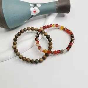 Dettaglio di braccialetti elastici in perle di agata naturale e pietre da 6 mm su sfondo bianco