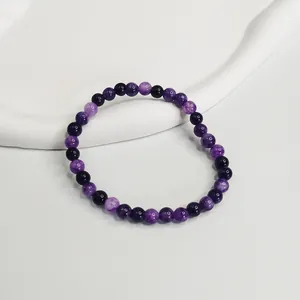 Dettaglio di un bracciale di perle di ametista viola da 6mm su espositore bianco opaco